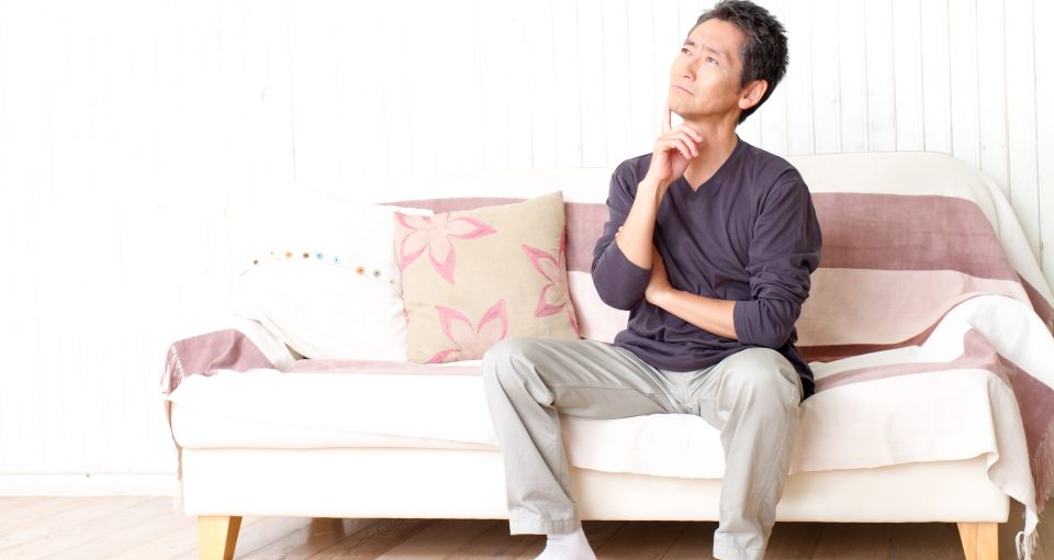 ソファに座って悩む男性