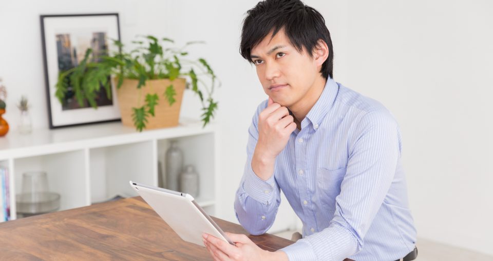 タブレットを眺めて悩む男性