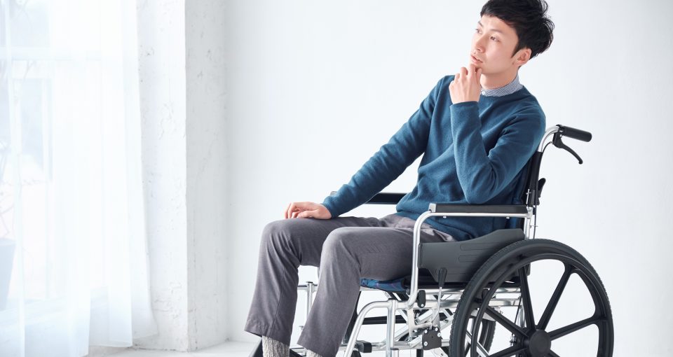 車いすに乗って悩む男性